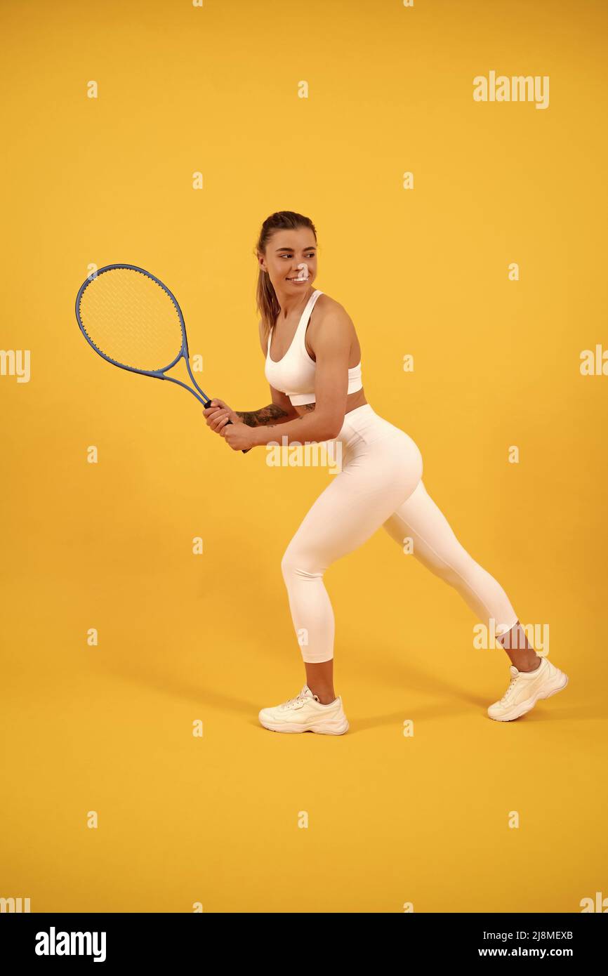 Lächelnder Tennisspieler läuft mit Schläger auf gelbem Hintergrund, Sport Stockfoto