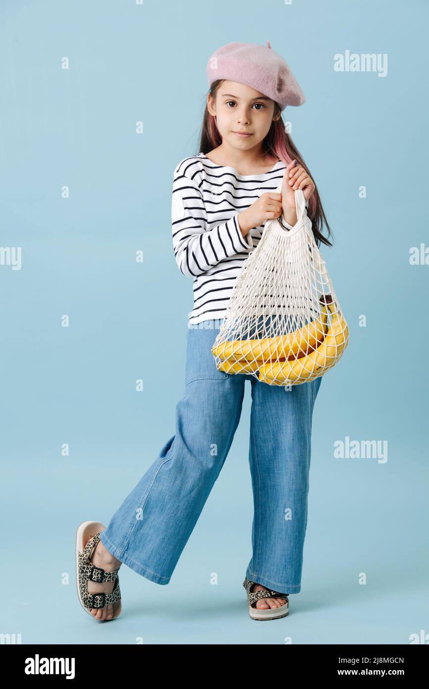 Modische Tween Mädchen in französisch Baskenmütze hält Netztasche mit Bananen. Stockfoto
