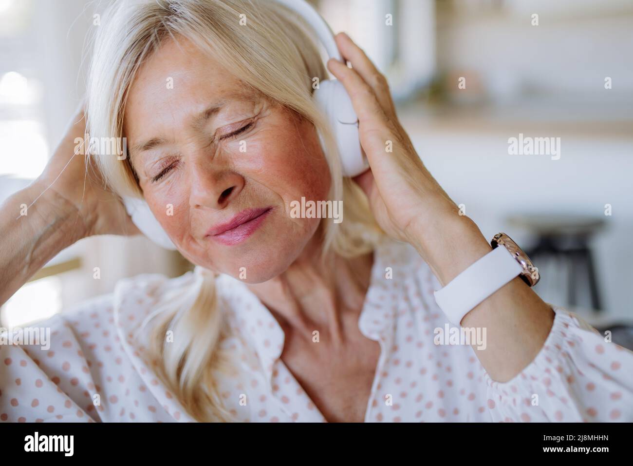 Ältere Frau mit Kopfhörern, die zu Hause Entspannungsmusik hört Stockfoto