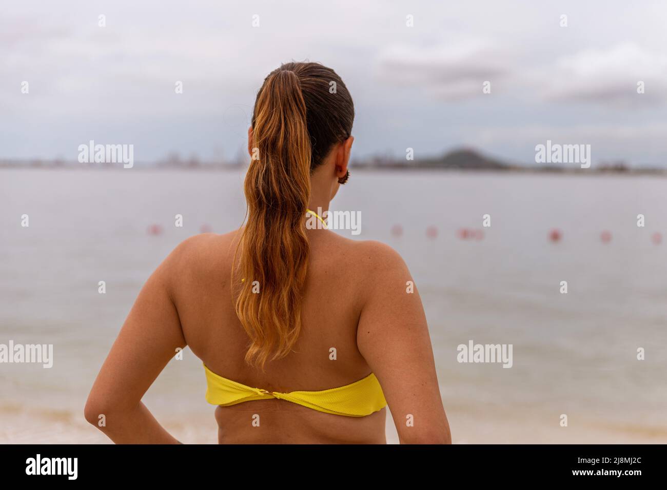 Rückansicht einer Latina-Frau, die im Bikini am Strand steht Stockfoto