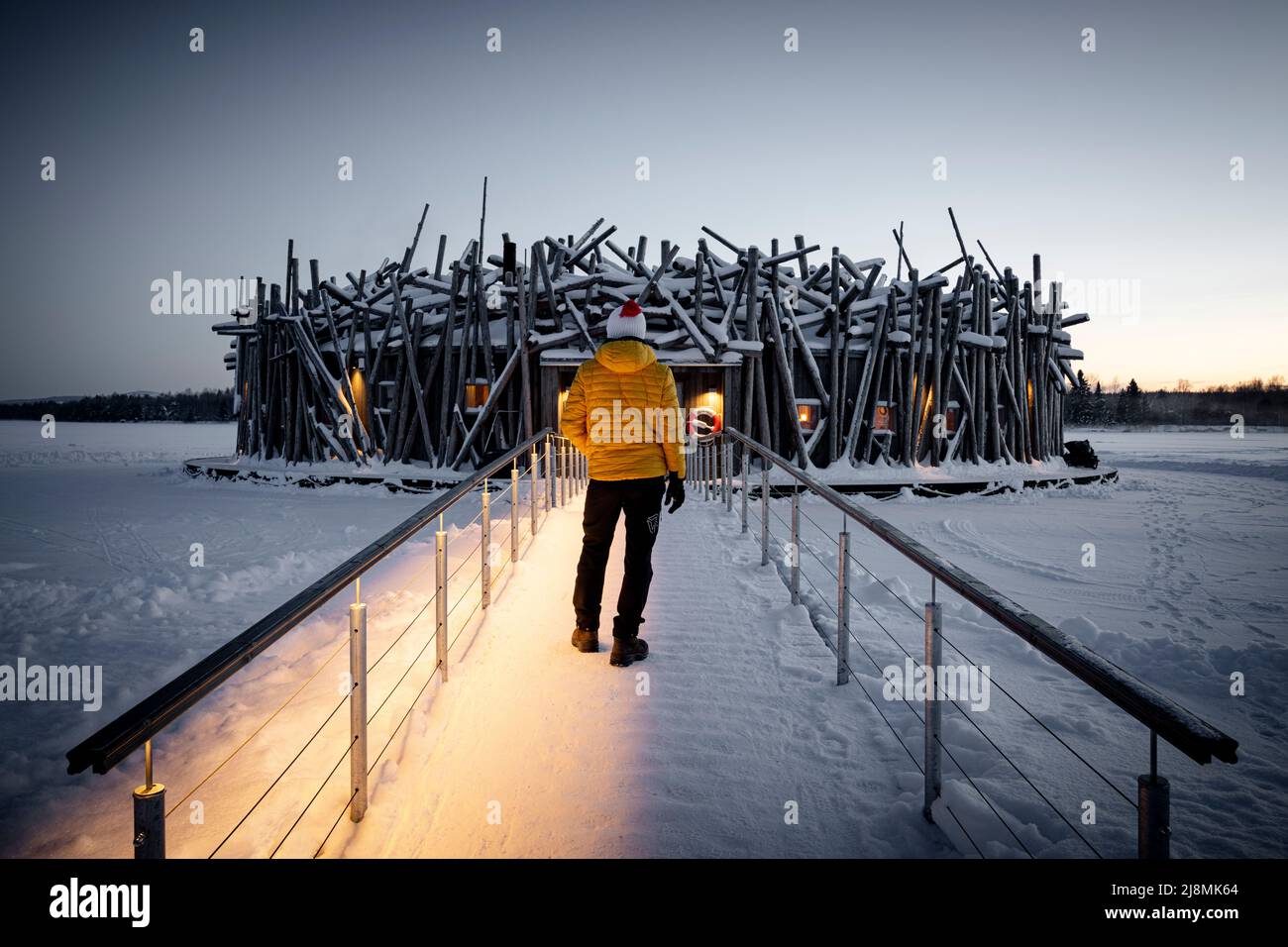 Person, die das runde Hauptgebäude des Arctic Bath Hotel aus Holz aus gefrorenem Gehweg bewundert, Harads, Lappland, Schweden Stockfoto