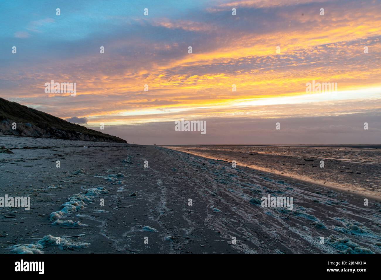 moody Sonnenuntergang mit Strand und Lichtreflexion im Meer Stockfoto