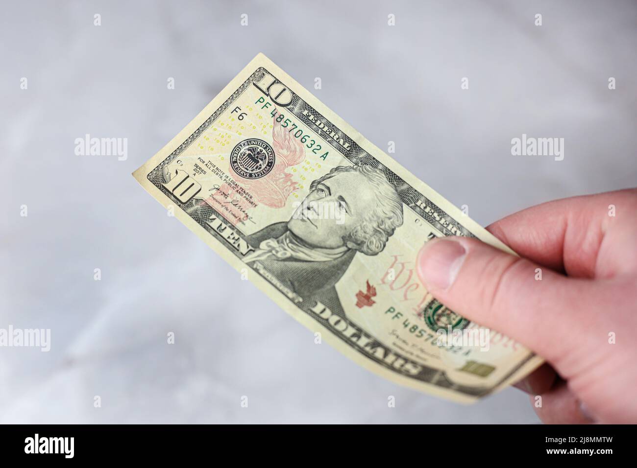 10 US-Dollar-Schein auf hellem Hintergrund in der Hand Stockfoto