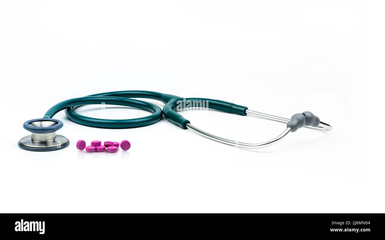 Grünes Stethoskop und Tablettenpillen auf weißem Hintergrund. Health Check. Kardiologische Ausrüstung für den Herzschlagtest. Gesundheitswesen und Medizin. Stockfoto