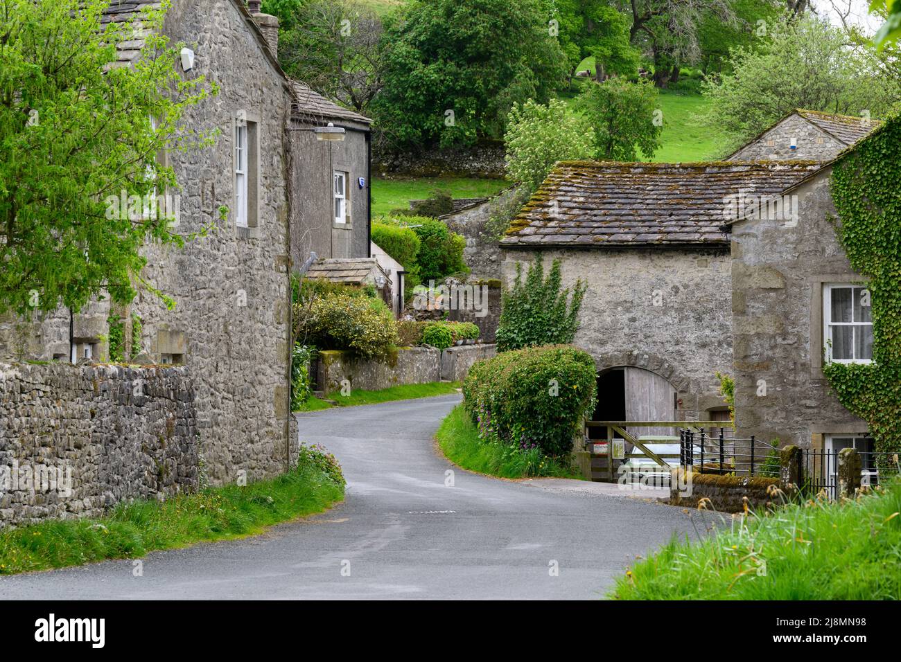Ruhiges Conistone Dorf (attraktive Steingebäude, grüne Felder auf steilen Talhängen, kurvenreiche Straße) - Wharfedale, Yorkshire Dales, England, Großbritannien. Stockfoto