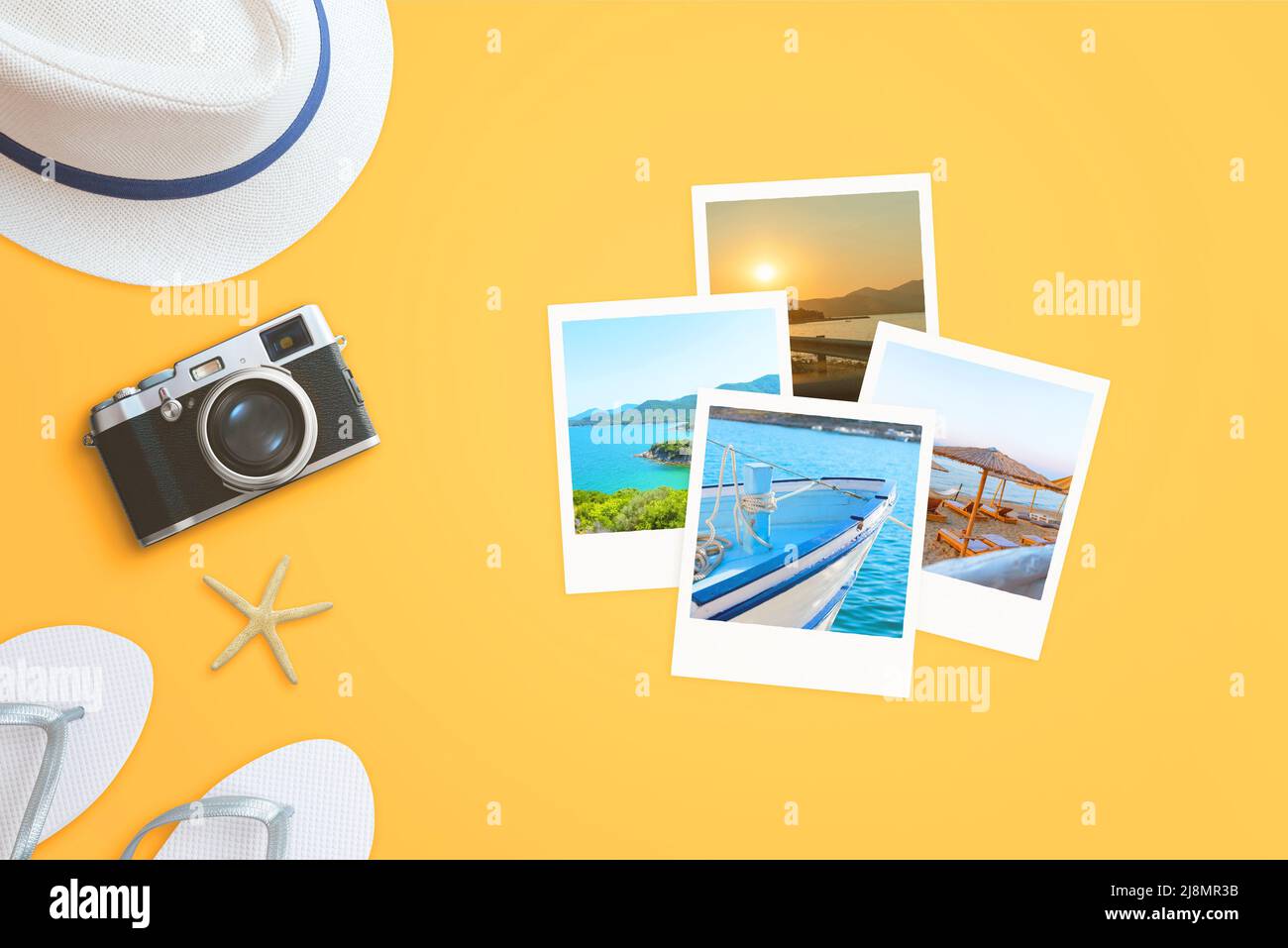 Reisebilder auf gelber Oberfläche mit Reisezubehör und Kamera daneben Stockfoto