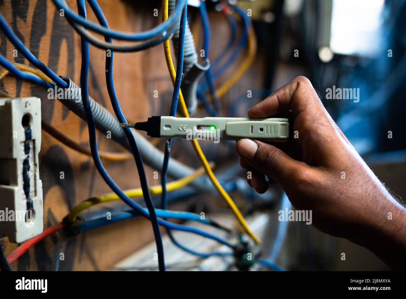 Nahaufnahme eines Elektrikers, der den Stromfluss mit einem Durchgangsspannungstester auf der Leiterplatte überprüft – Konzept für Technologie, Reparatur und Wartung Stockfoto