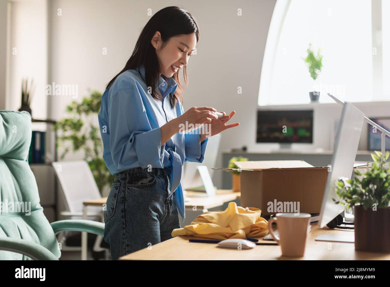 Glückliche asiatische Frau, die das Hemd fotografiert Stockfoto