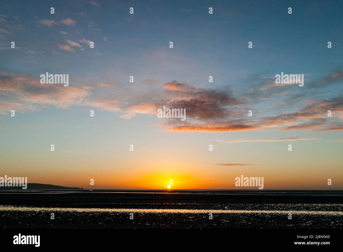 Sonnenaufgang bei Ebbe mit goldenem Licht und dünnen Zirruswolken. Sandymount Beach, Dublin, Irland Stockfoto