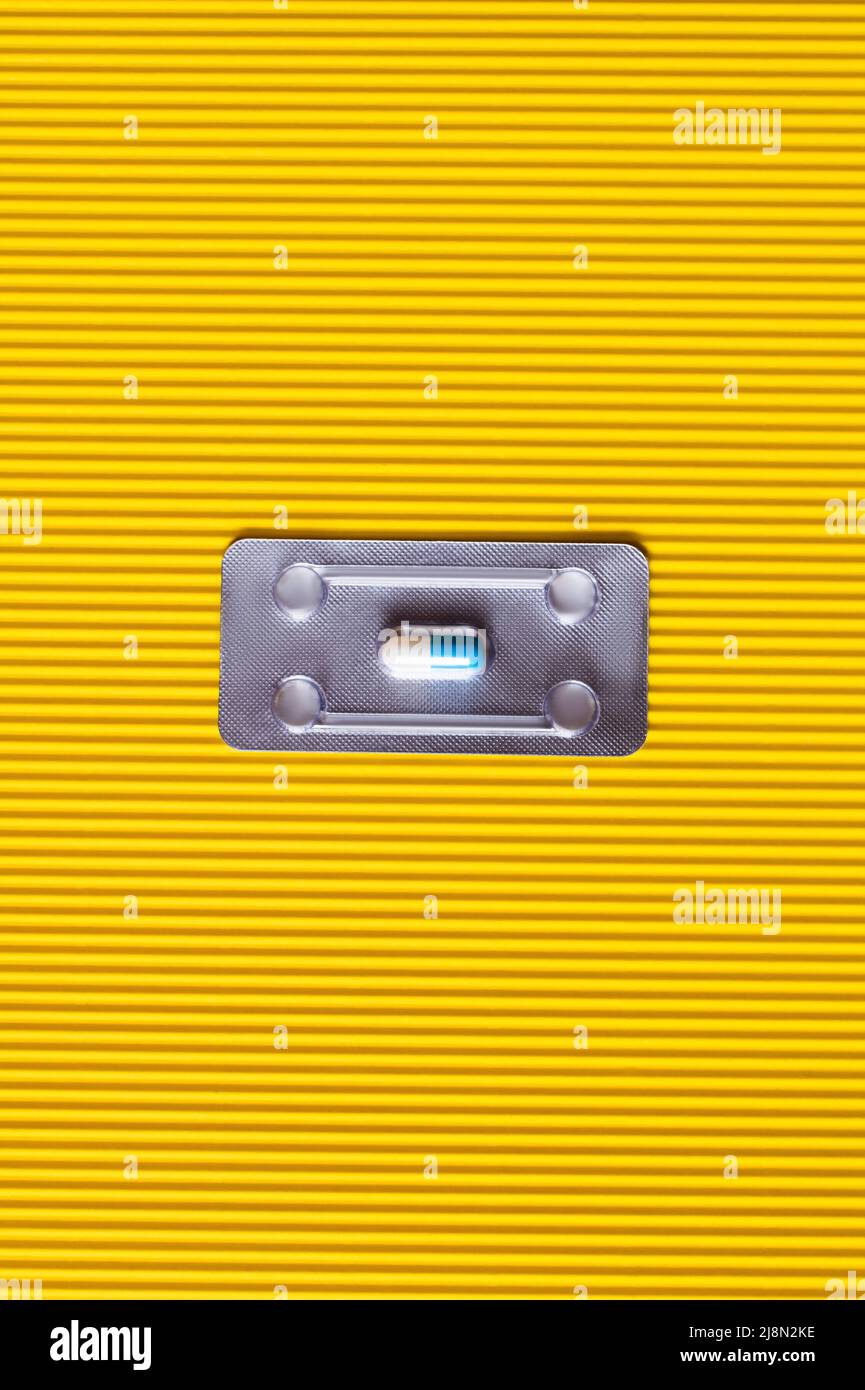 Draufsicht auf Blisterpackung mit Antibiotika-Kapsel auf strukturiertem gelben Hintergrund Stockfoto