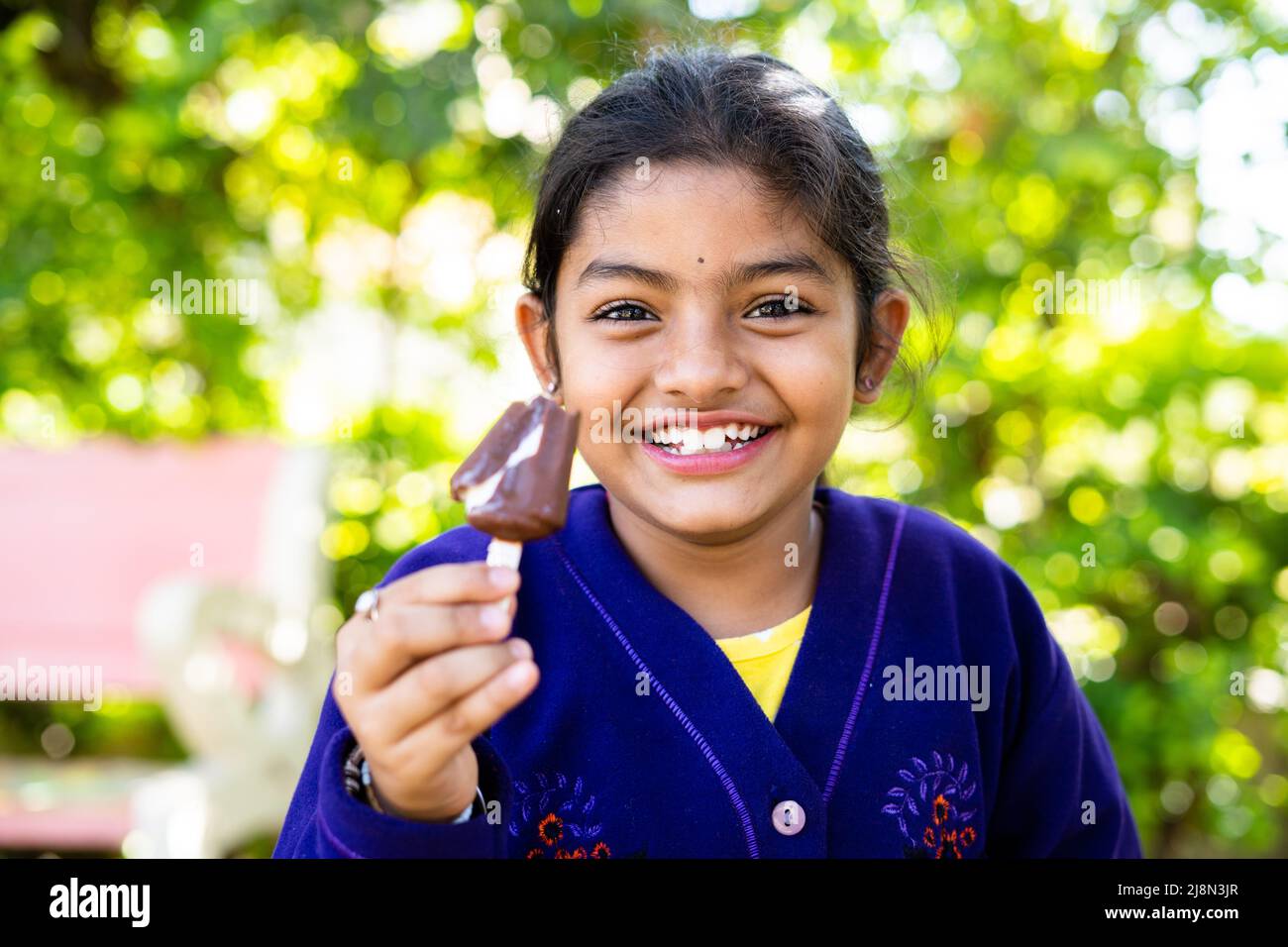 Glücklich lächelndes Mädchen Kind im Winter tragen Eis essen im Park - Konzept der Ferien, sorglos und Entspannung. Stockfoto