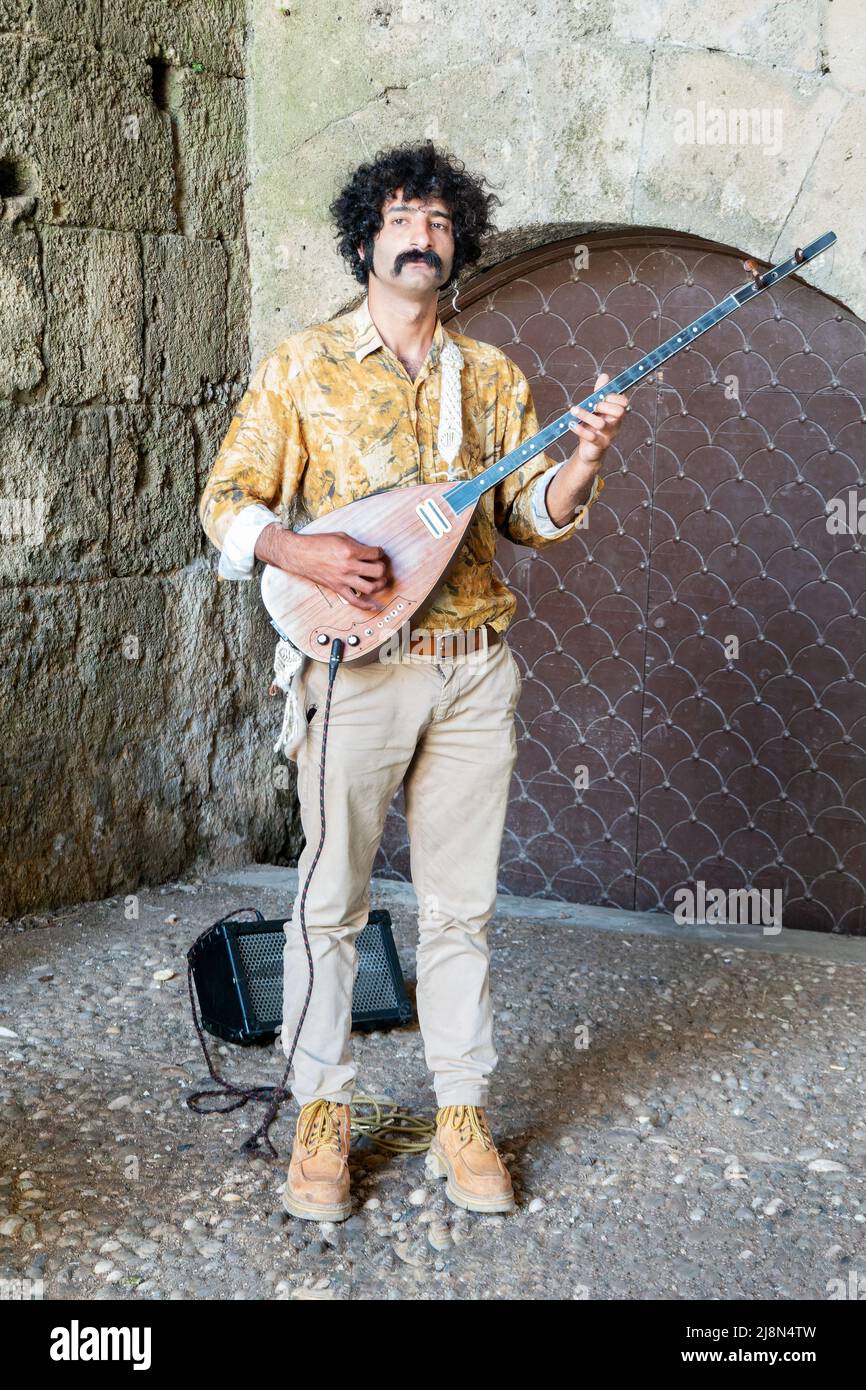 Ein männlicher Straßenmusiker, der ein Bouzouki spielt, ein griechisches Saiteninstrument. Der Musiker befindet sich in einer Nische in der Altstadt von Rhodos, Rhodos, Griechenland Stockfoto