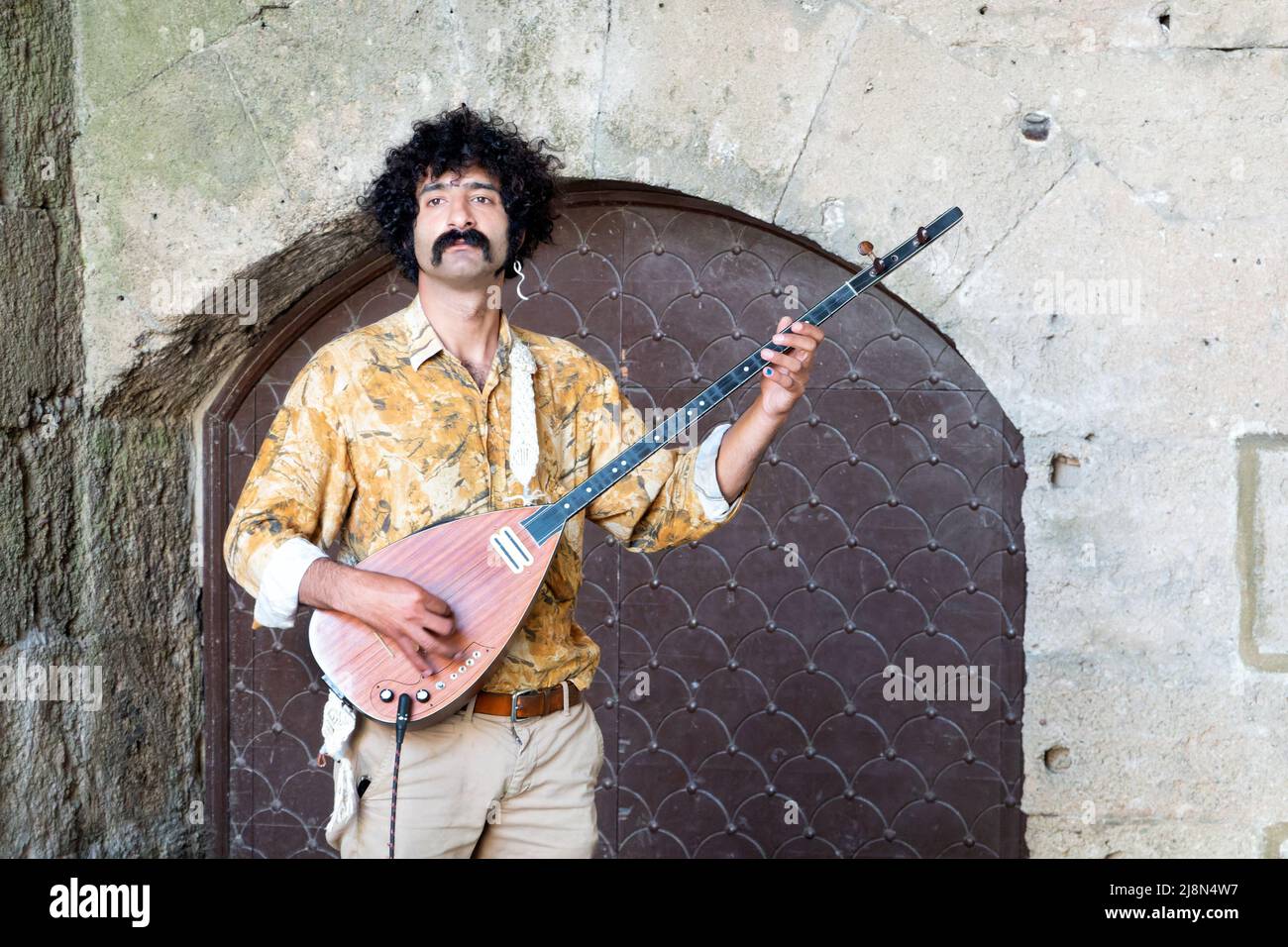 Ein männlicher Straßenmusiker, der ein Bouzouki spielt, ein griechisches Saiteninstrument. Der Musiker befindet sich in einer Nische in der Altstadt von Rhodos, Rhodos, Griechenland Stockfoto
