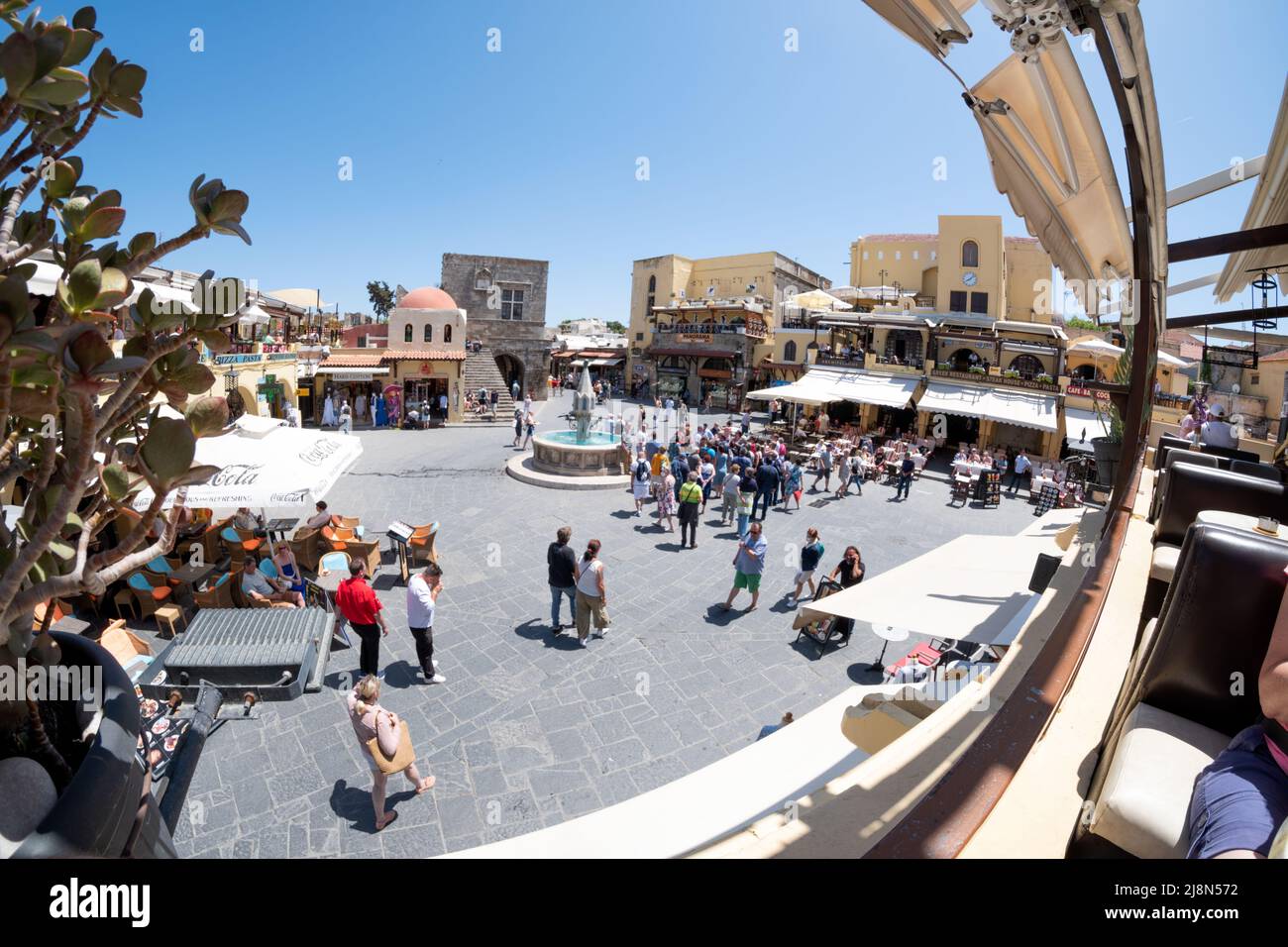 Ein Blick über den Hippokrates-Platz, die Altstadt von Rhodos, Rhodos, Griechenland. Das Bild zeigt Touristen und eine geführte Tour, die sich unter die berühmte Attraktion mischen Stockfoto