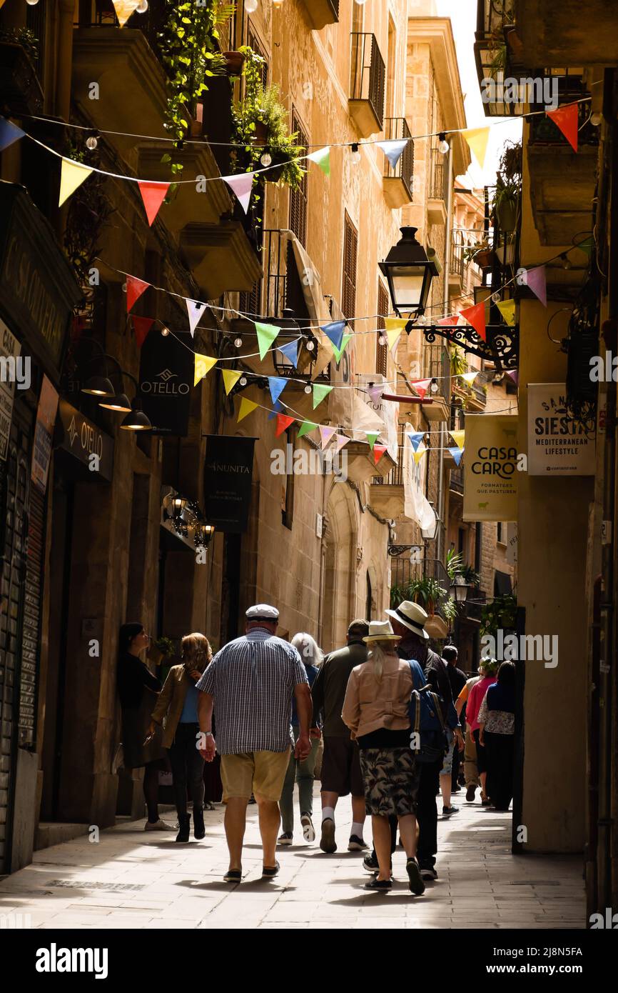 Touristen, die durch die engen Straßen von Barcelona im Barrio Gotico spazieren. Stockfoto