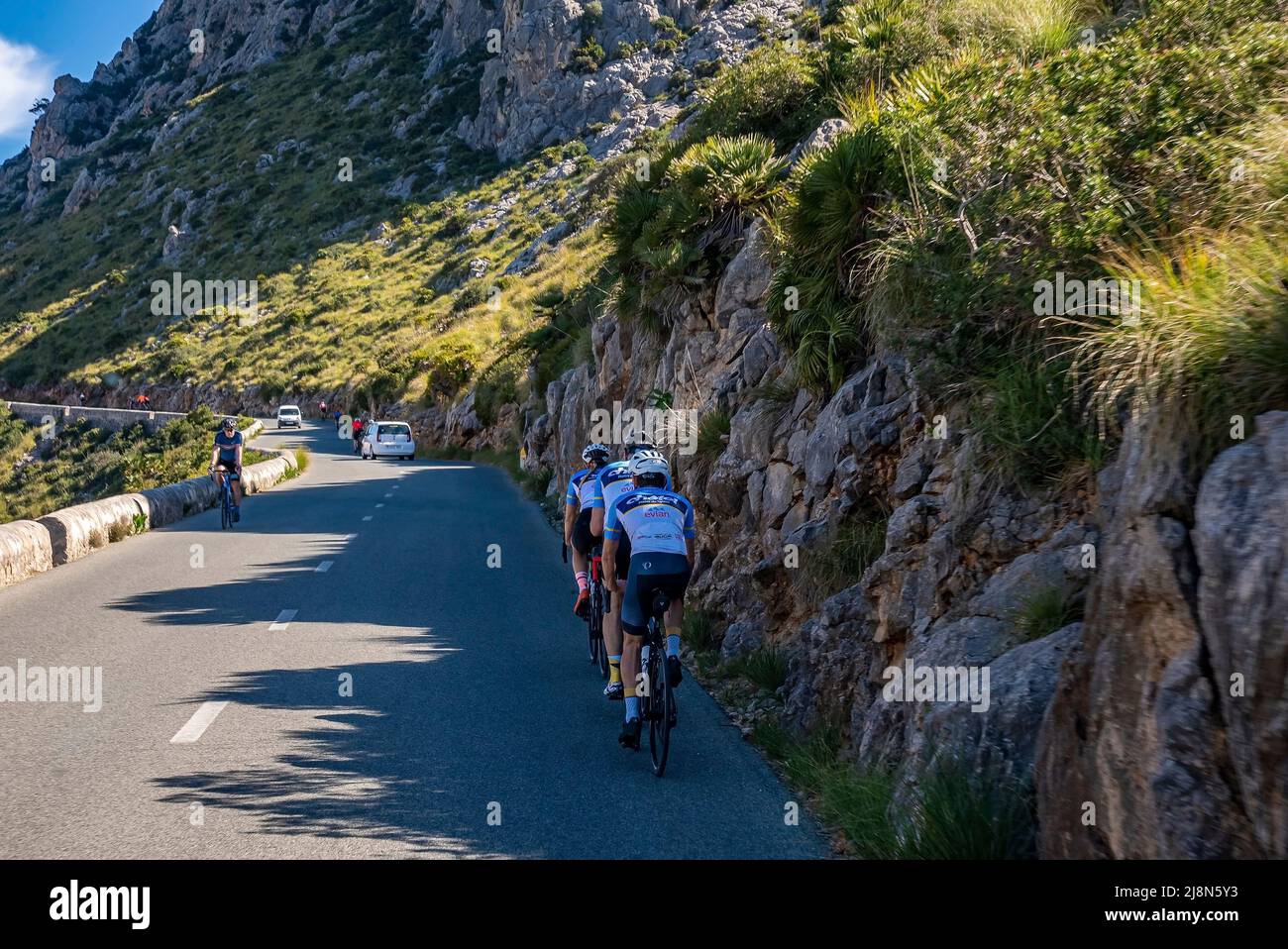 Radfahrer radeln im Schatten auf der Landstraße durch die Berge an sonnigen Tagen Stockfoto