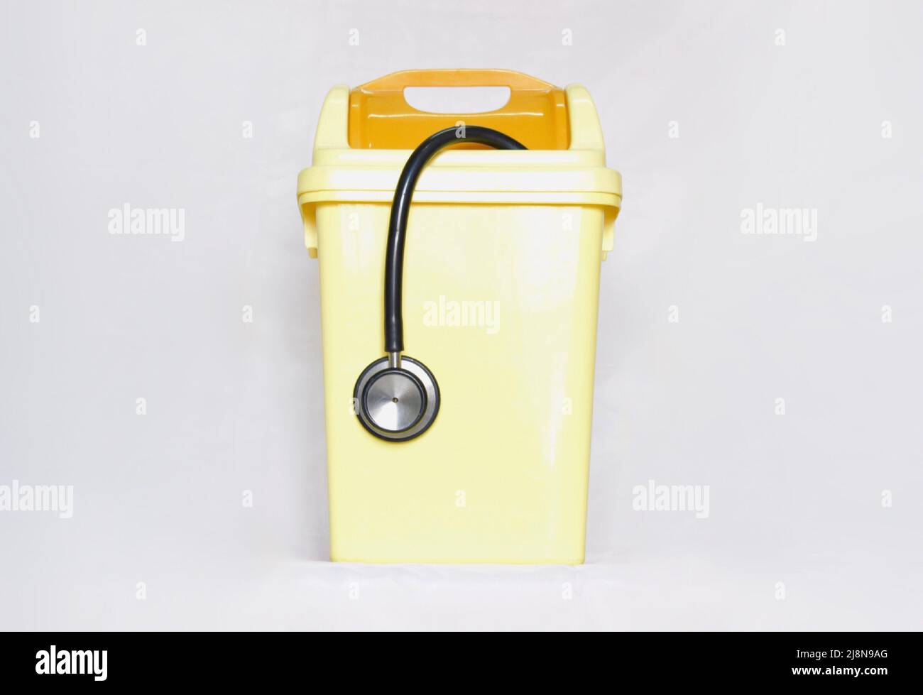 Schwarzes Stethoskop in kleinen gelben Kunststoff-Abfalleimer. Zeigt, beenden Sie den medizinischen Job, enttäuschen und aufgeben Ärzteberuf. Stockfoto