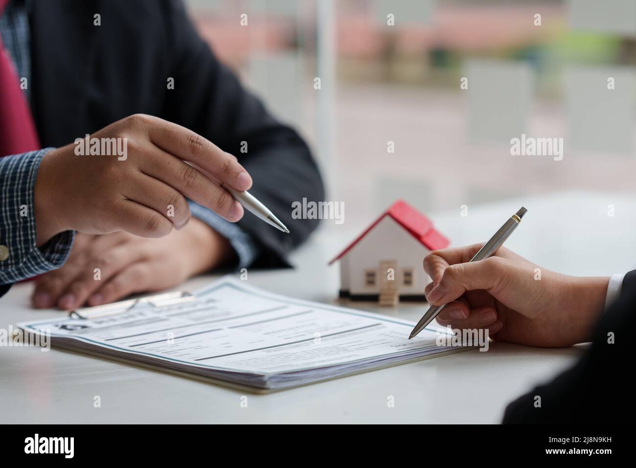 Nahaufnahme des Geschäftsmanns, der auf den Kauf eines Hauses hinweist und eine Vereinbarung unterzeichnet. Konzept des Bankleiters. Stockfoto