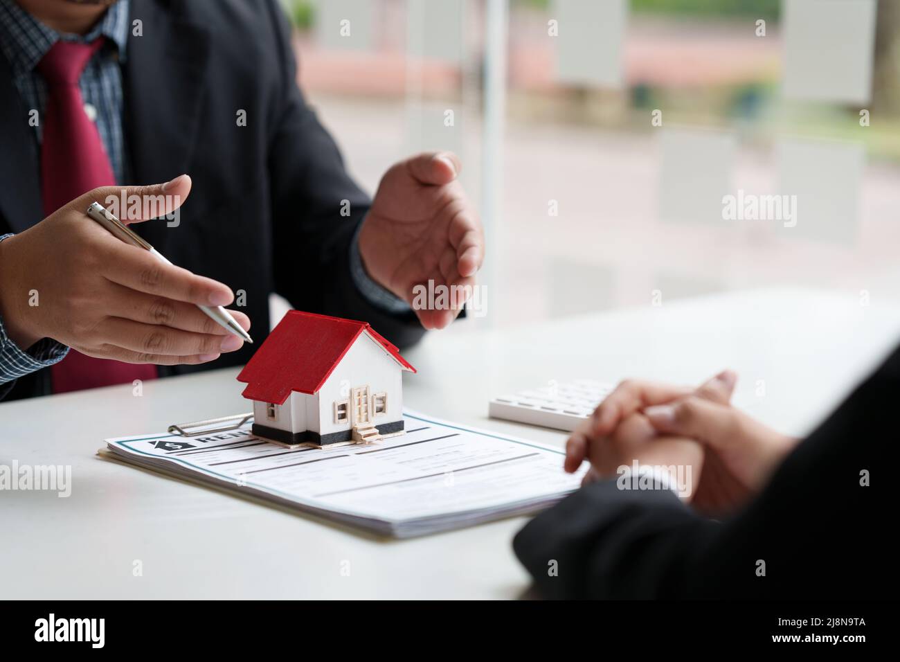 Nahaufnahme des Geschäftsmanns, der auf den Kauf eines Hauses hinweist und eine Vereinbarung unterzeichnet. Konzept des Bankleiters. Stockfoto