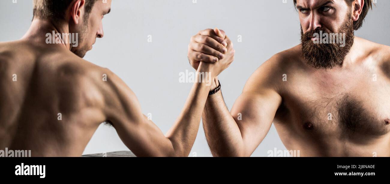 Zwei Männerhände umspannten Arm Wrestling, stark und schwach, ungleich. Armdrücken. Stark muskulös bärtiger Mann, der einen schwach schwachen Mann am Arm kämpft. Arme Stockfoto