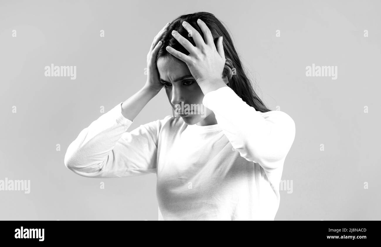 Brünette Frau berührt ihre Tempel Gefühl Stress, auf grauem Hintergrund. Frau, die an Kopfschmerzen leidet, verzweifelt, gestresst, weil Schmerzen und Migräne Stockfoto