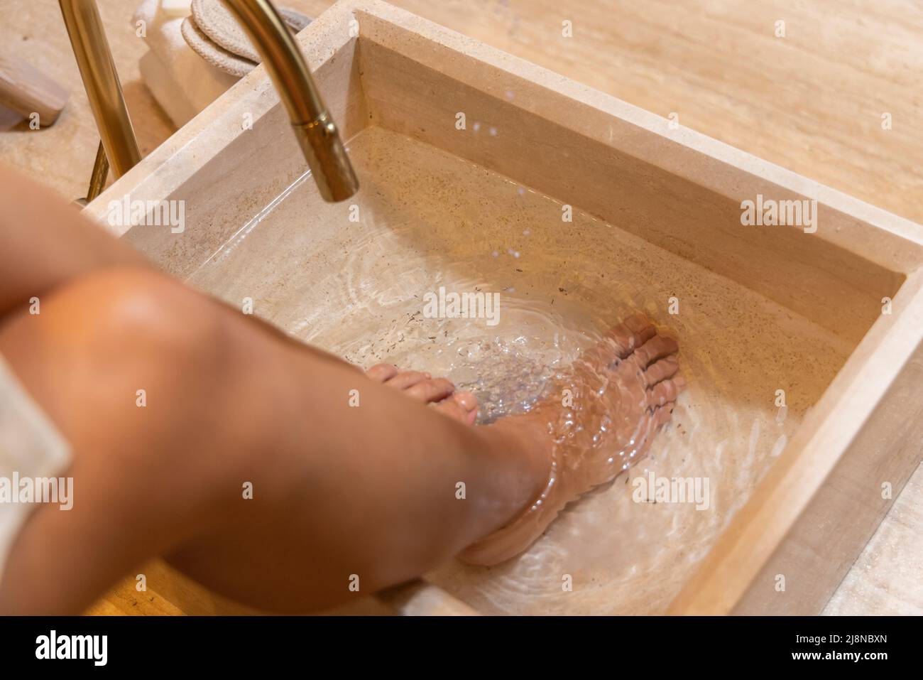 Mädchen, das sich auf die Pediküre vorbereitet und ihre Füße in Wasser einweicht. Stockfoto