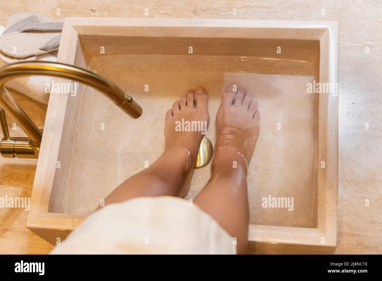 Mädchen, das sich auf die Pediküre vorbereitet und ihre Füße in Wasser einweicht. Stockfoto