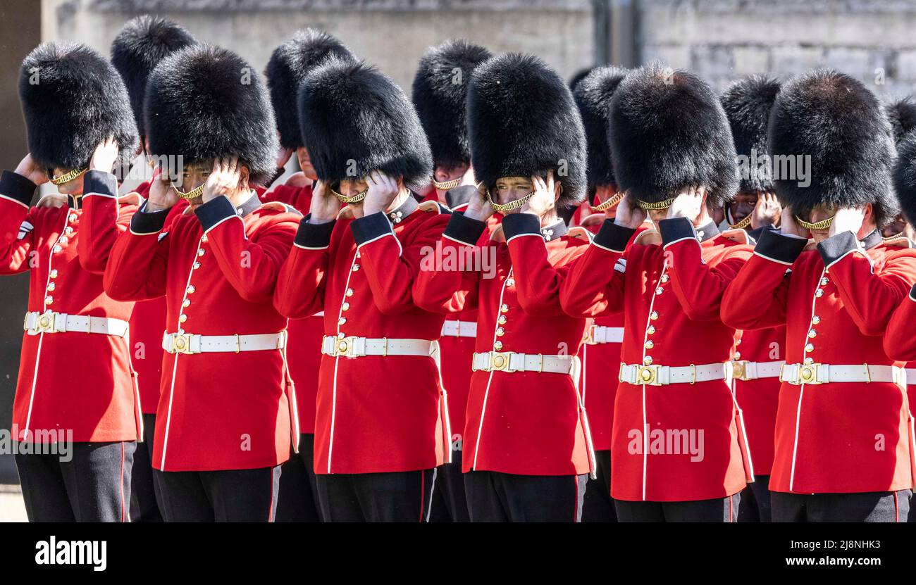 Die Wächter der 1. irischen Bataillone entfernen ihre zeremoniellen Bärenfellhüte während der Parade im Viereck von Windsor Castle, wo ihnen ihre neuen Regimentsfarben vom Herzog von Cambridge überreicht wurden. Bilddatum: Dienstag, 17. Mai 2022. Stockfoto