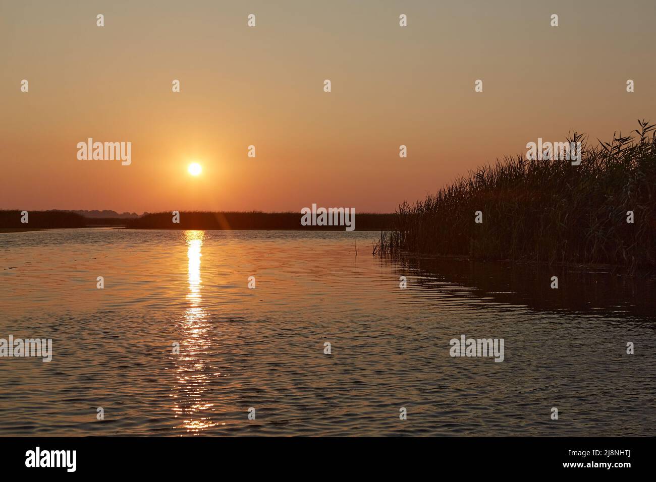 Sonnenuntergang über einem ruhigen See, Wasserwellenspiegelung Stockfoto