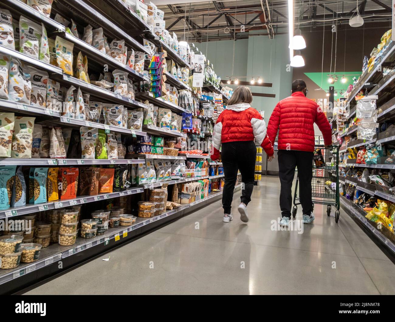Kirkland, WA USA - ca. Februar 2022: Blick auf ein süßes Paar in passenden roten Jacken, das sich gegenseitig hält, während sie einen Whole Foods Market durchstöbern. Stockfoto