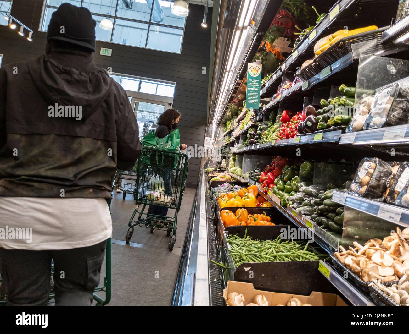 Lynnwood, WA USA - ca. April 2022: Schräge Ansicht einer Frau, die in einem Whole Foods Market Gemüse kauft Stockfoto