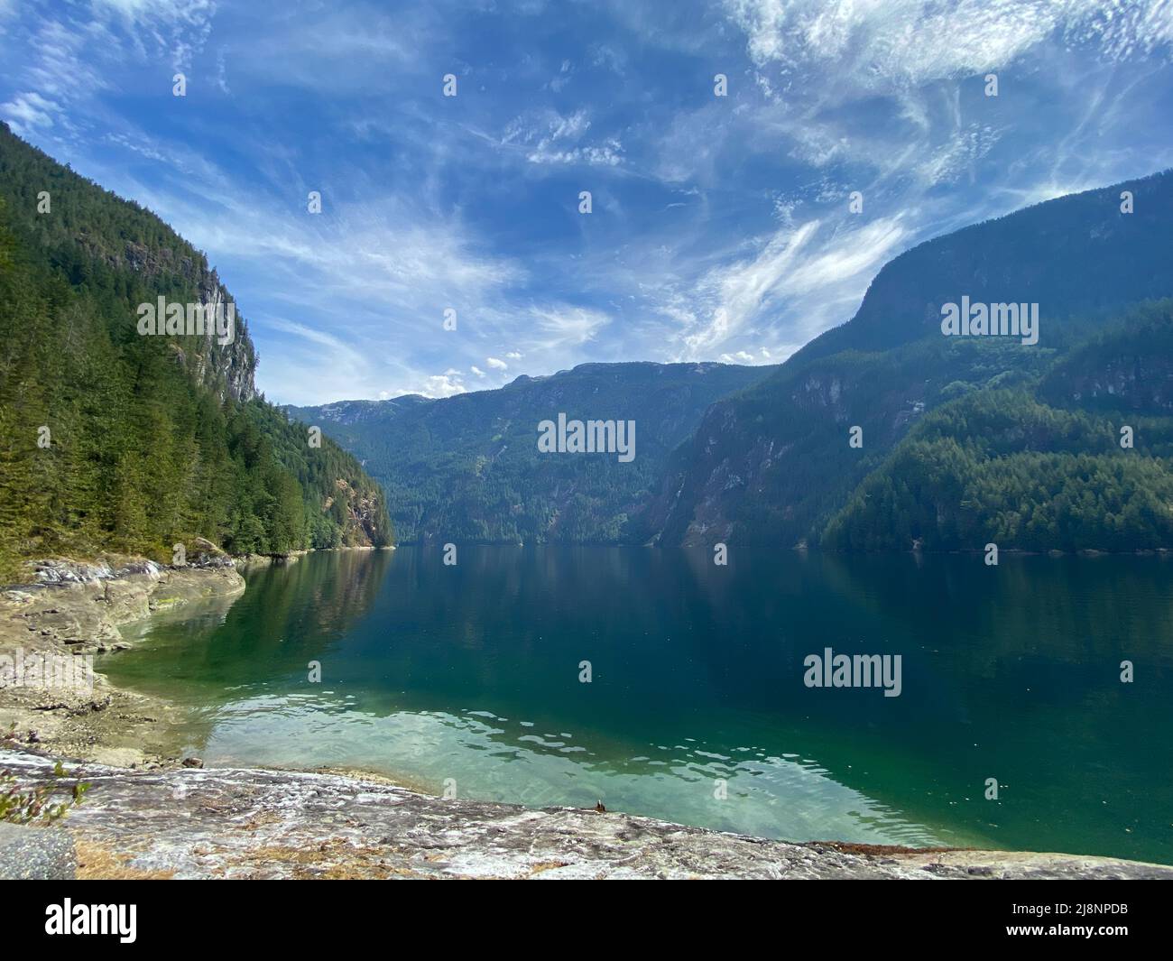 Blick auf den Princess Louisa Inlet in der Nähe von MacDonald Island mit riesigen Bergen im Hintergrund und grünem Wasser an der Sunshine Coast von British Columbia, Kanada Stockfoto