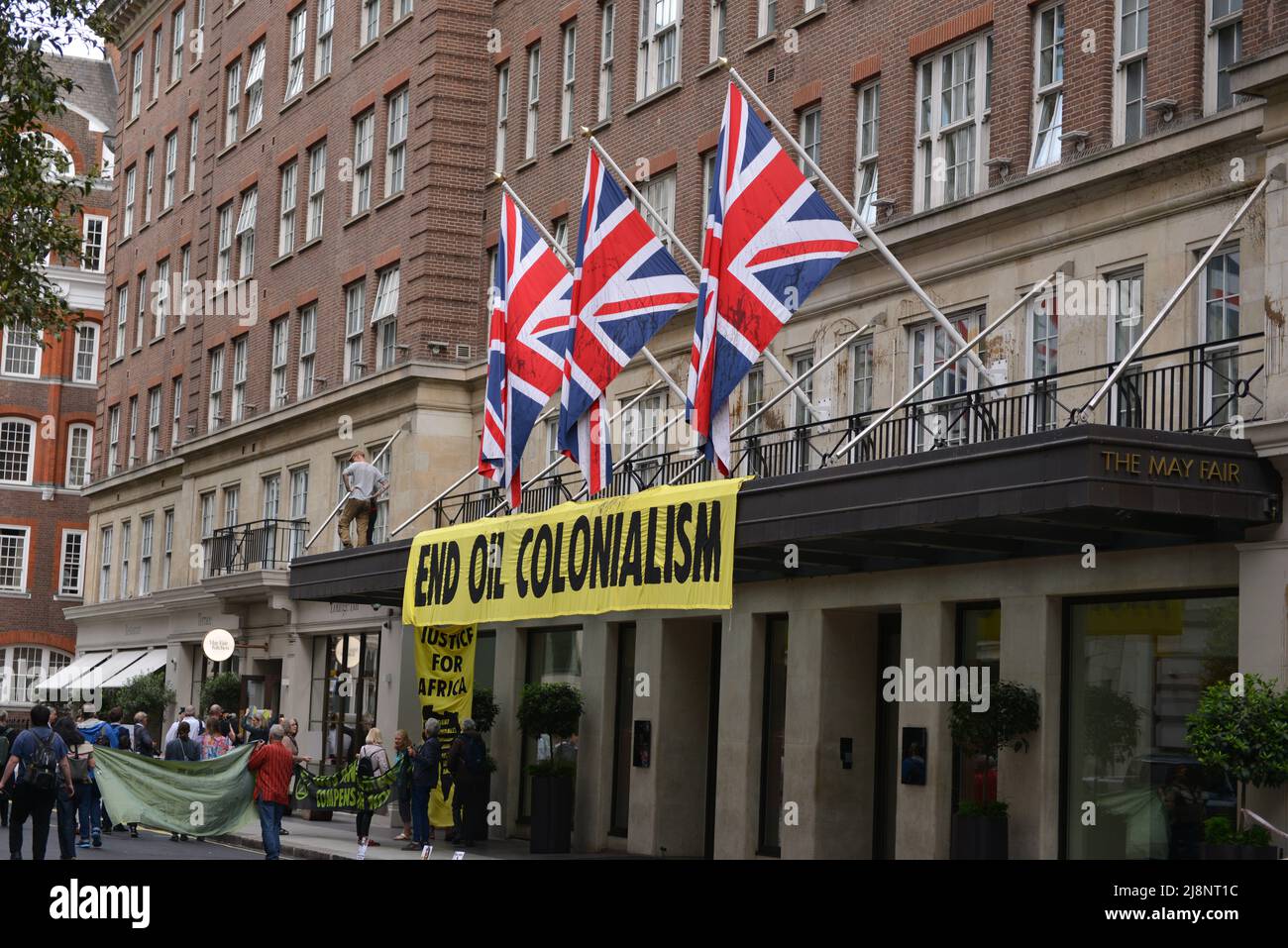 Aktivisten entrollten ein Banner mit der Aufschrift End Oil Colonialism. Aktivisten des Extinction Rebellion stürmen das May Fair Hotel im Zentrum von London aus Protest gegen einen Ölgipfel (Africa Energies Summit), der im fünf-Sterne-Hotel stattfindet. Stockfoto
