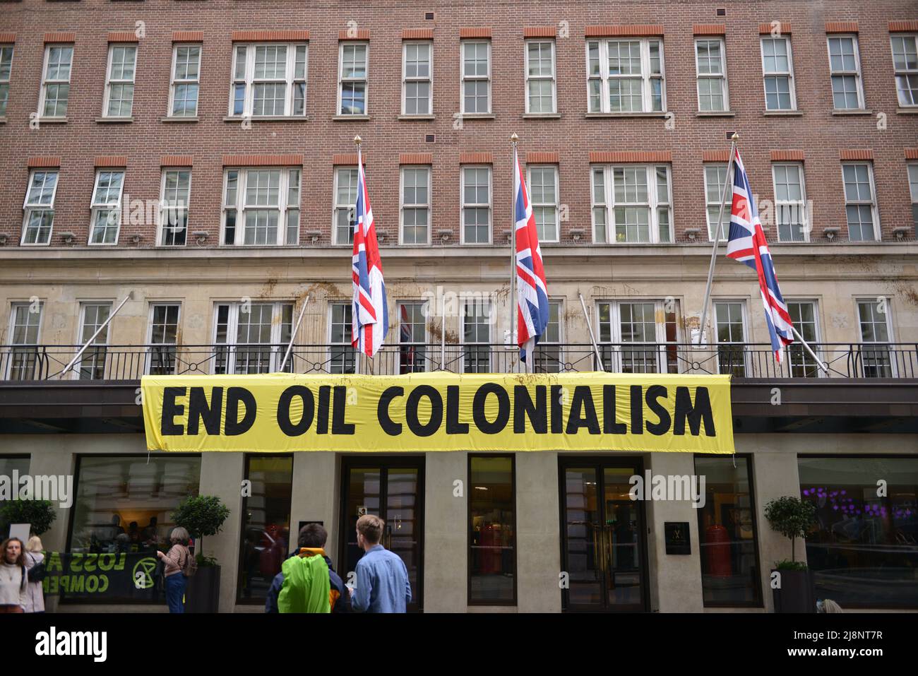 Aktivisten entrollten ein Banner mit der Aufschrift End Oil Colonialism. Aktivisten des Extinction Rebellion stürmen das May Fair Hotel im Zentrum von London aus Protest gegen einen Ölgipfel (Africa Energies Summit), der im fünf-Sterne-Hotel stattfindet. Stockfoto