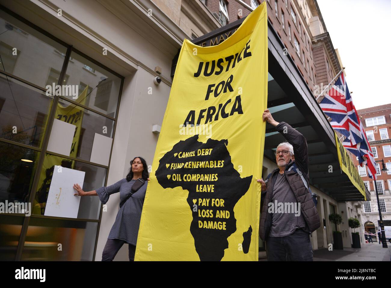 Aktivisten halten vor dem May Fair Hotel ein Transparent mit dem Slogan „Gerechtigkeit für Afrika“. Aktivisten des Extinction Rebellion stürmen das May Fair Hotel im Zentrum von London aus Protest gegen einen Ölgipfel (Africa Energies Summit), der im fünf-Sterne-Hotel stattfindet. Stockfoto