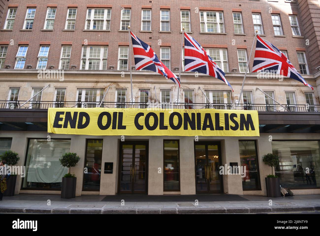 Aktivisten entrollten ein Banner mit der Aufschrift End Oil Colonialism. Aktivisten des Extinction Rebellion stürmen das May Fair Hotel im Zentrum von London aus Protest gegen einen Ölgipfel (Africa Energies Summit), der im fünf-Sterne-Hotel stattfindet. Stockfoto
