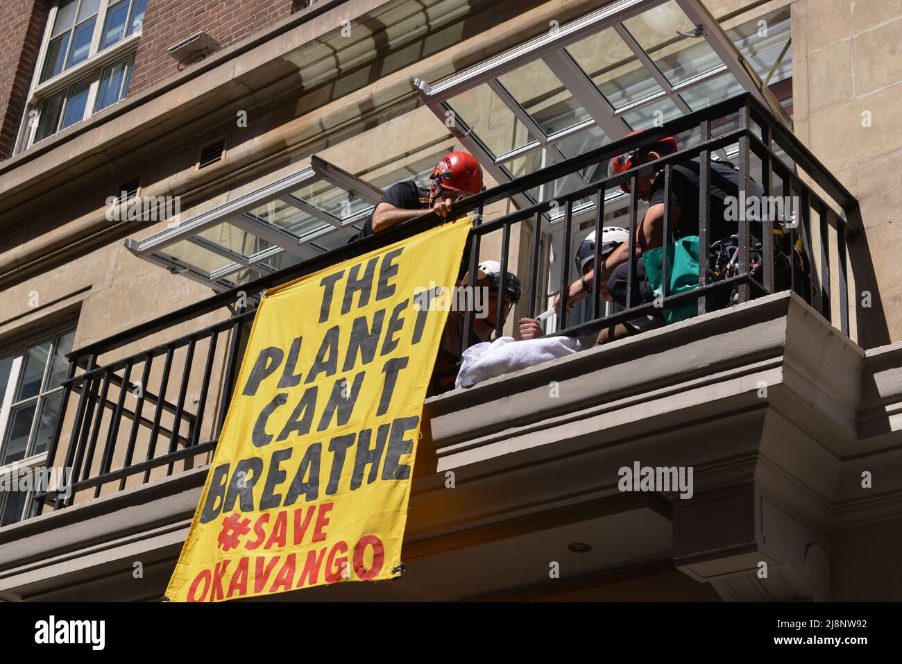 Die Polizisten lösen den Leim aus den Händen der Aktivisten auf dem Balkon des May Fair Hotels. Aktivisten des Extinction Rebellion stürmen das May Fair Hotel im Zentrum von London aus Protest gegen einen Ölgipfel (Africa Energies Summit), der im fünf-Sterne-Hotel stattfindet. Stockfoto
