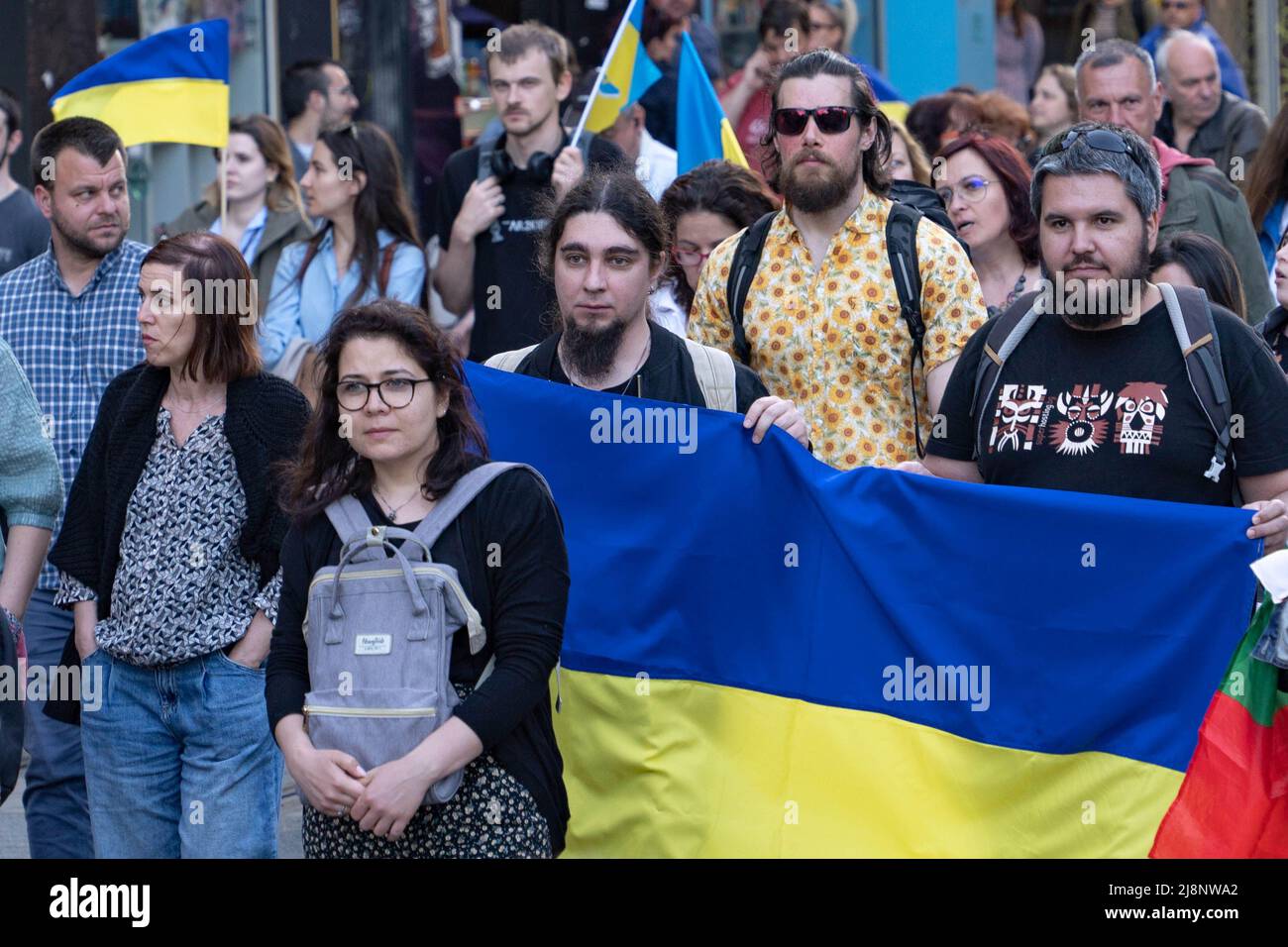 Sofia, Bulgarien - 09. Mai 2022: Zwei Männer halten eine große ukrainische Flagge vor sich und gehen in einer Menschenmenge Stockfoto