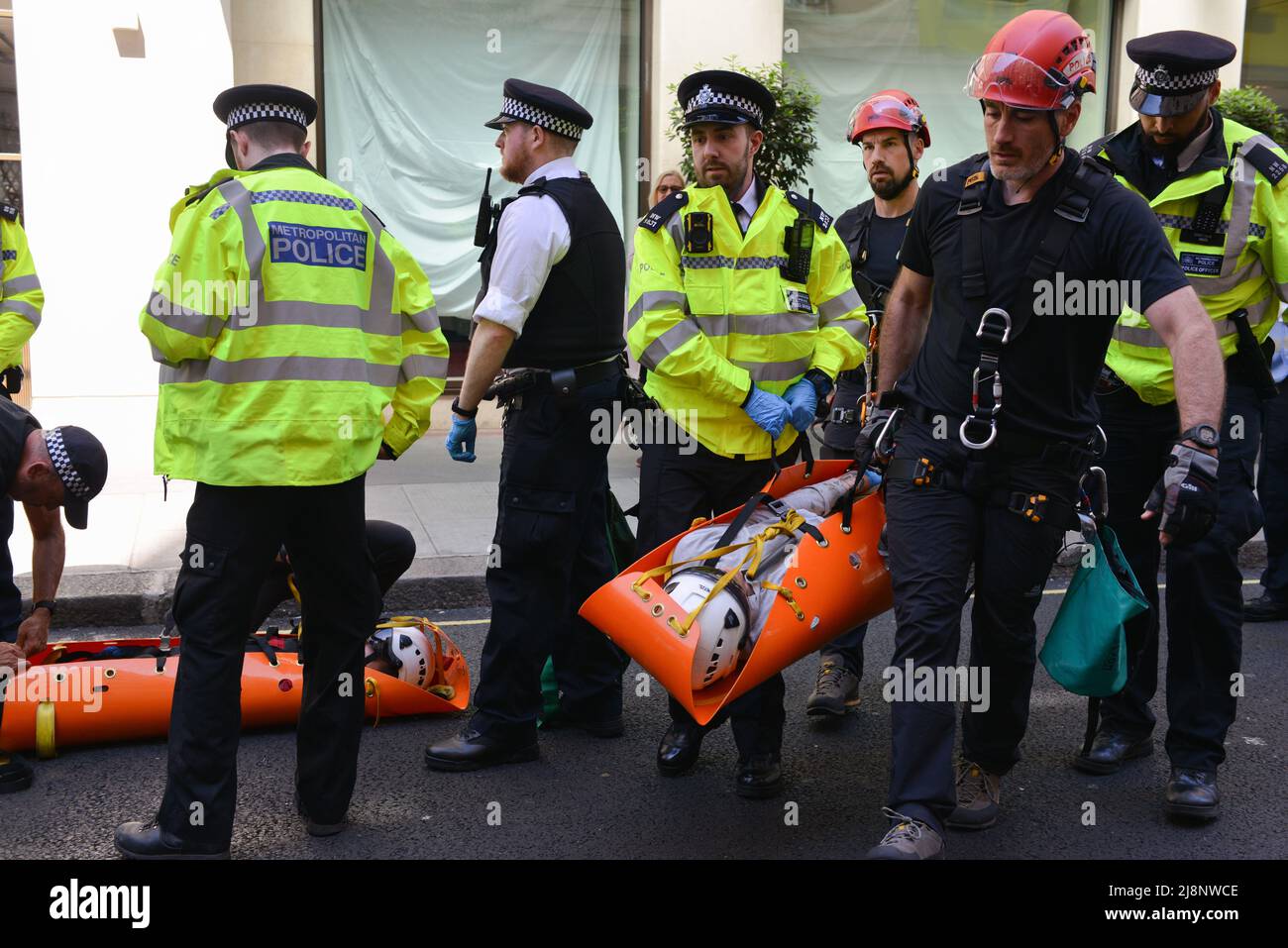 Ein festgenommener Aktivist wird von der Polizei auf einer Bahre getragen, nachdem er vom Balkon des May Fair Hotels entfernt wurde. Aktivisten des Extinction Rebellion stürmen das May Fair Hotel im Zentrum von London aus Protest gegen einen Ölgipfel (Africa Energies Summit), der im fünf-Sterne-Hotel stattfindet. Stockfoto