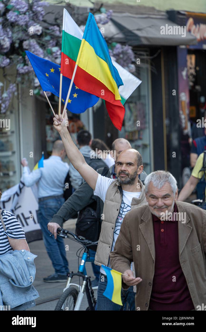 Ein Mann geht in einer Menschenmenge mit einem Medium, das die Flaggen der Europäischen Union, Bulgariens und der Ukraine in der Hand hebt Stockfoto