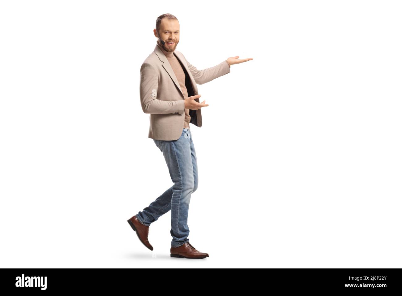 Die ganze Aufnahme eines jungen Mannes mit einem Headset zeigt etwas mit isolierten Händen auf weißem Hintergrund Stockfoto