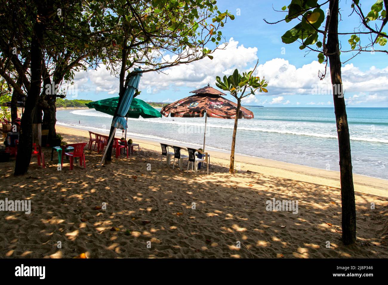 Kuta Beach Szene in Bali, Indonesien im März 2022 während der Pandemie mit wenigen Touristen, Getränkeverkäufern, Sonnenschirmen und einem ruhigen Strand. Stockfoto