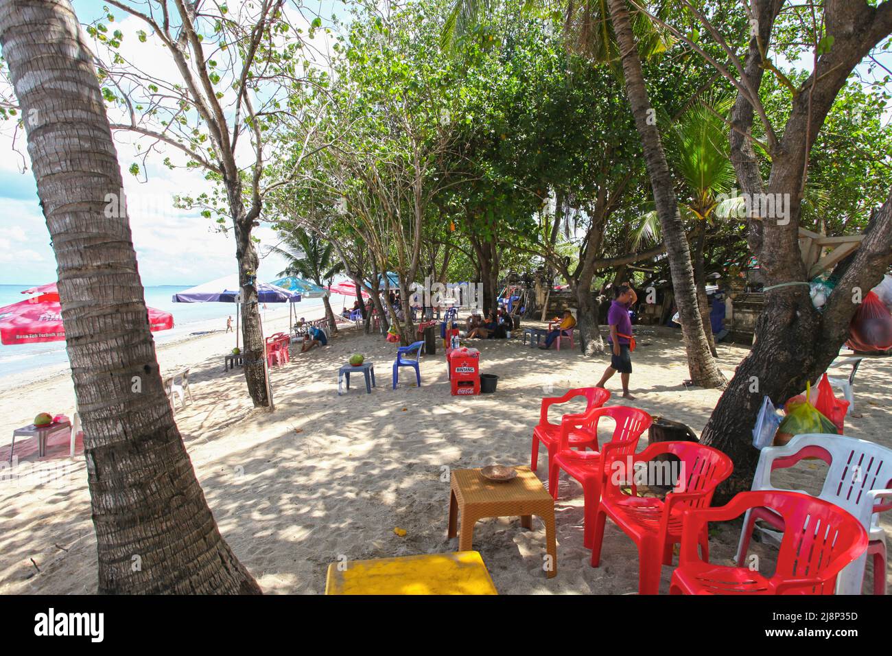 Kuta Beach Szene in Bali, Indonesien im März 2022 während der Pandemie mit wenigen Touristen, Getränkeverkäufern, Sonnenschirmen und einem ruhigen Strand. Stockfoto