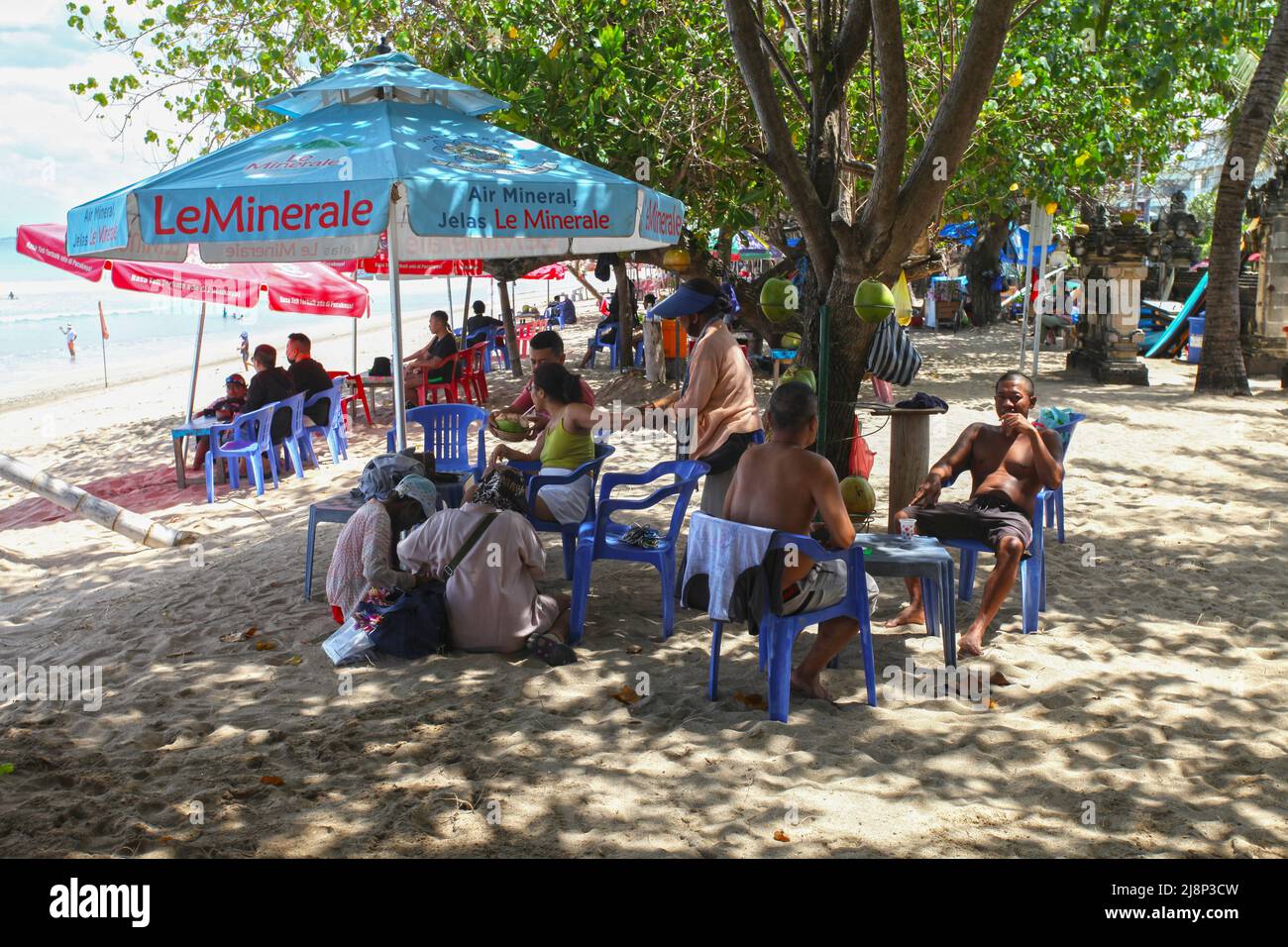 Kuta Beach Szene in Bali, Indonesien im März 2022 während der Pandemie mit wenigen Touristen, Getränkeverkäufern, Sonnenschirmen und einem ruhigen Strand. Stockfoto