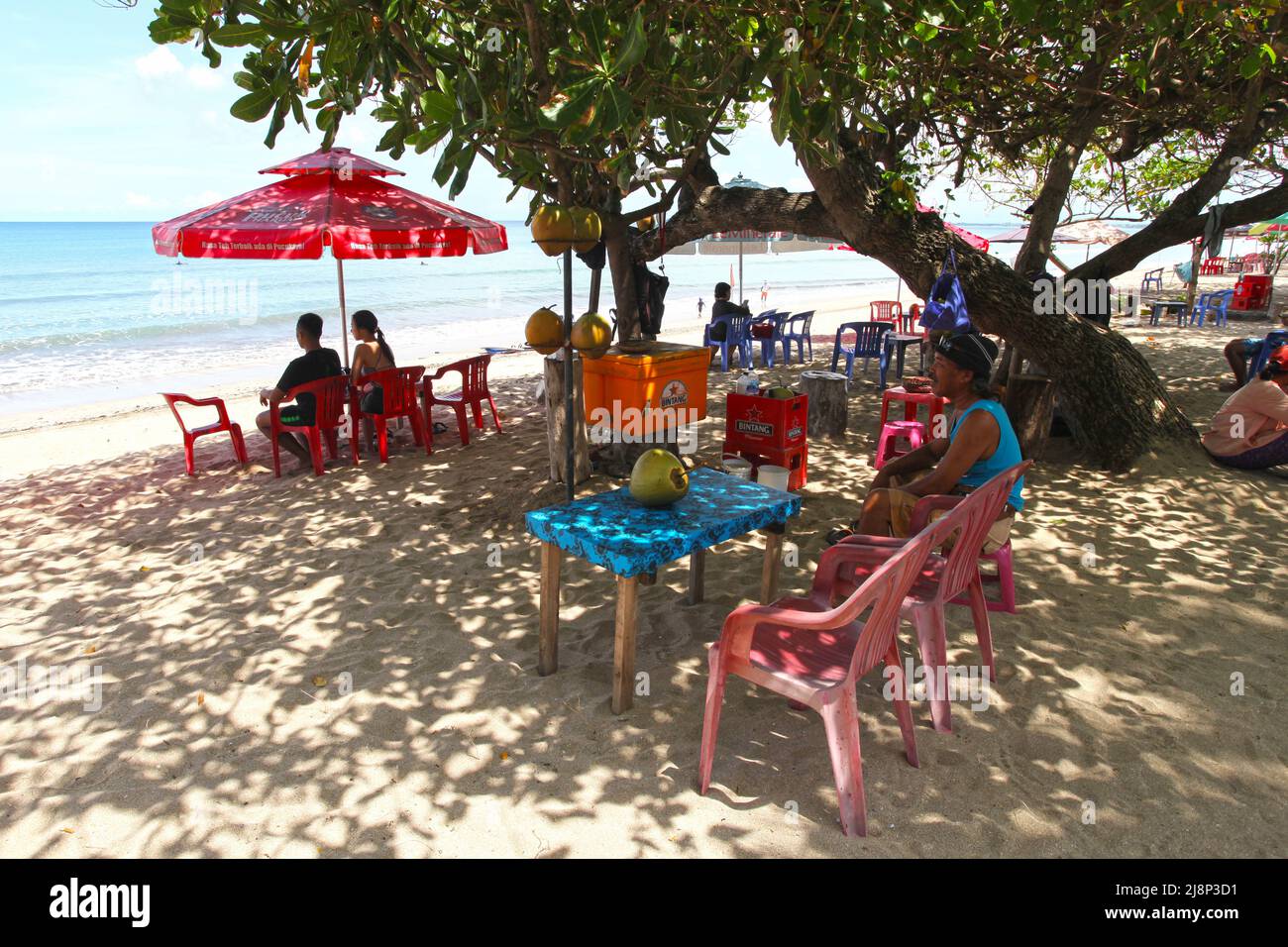 Kuta Beach Szene in Bali, Indonesien im März 2022 während der Pandemie mit wenigen Touristen, Getränkeverkäufern, Sonnenschirmen und einem ruhigen Strand. Stockfoto