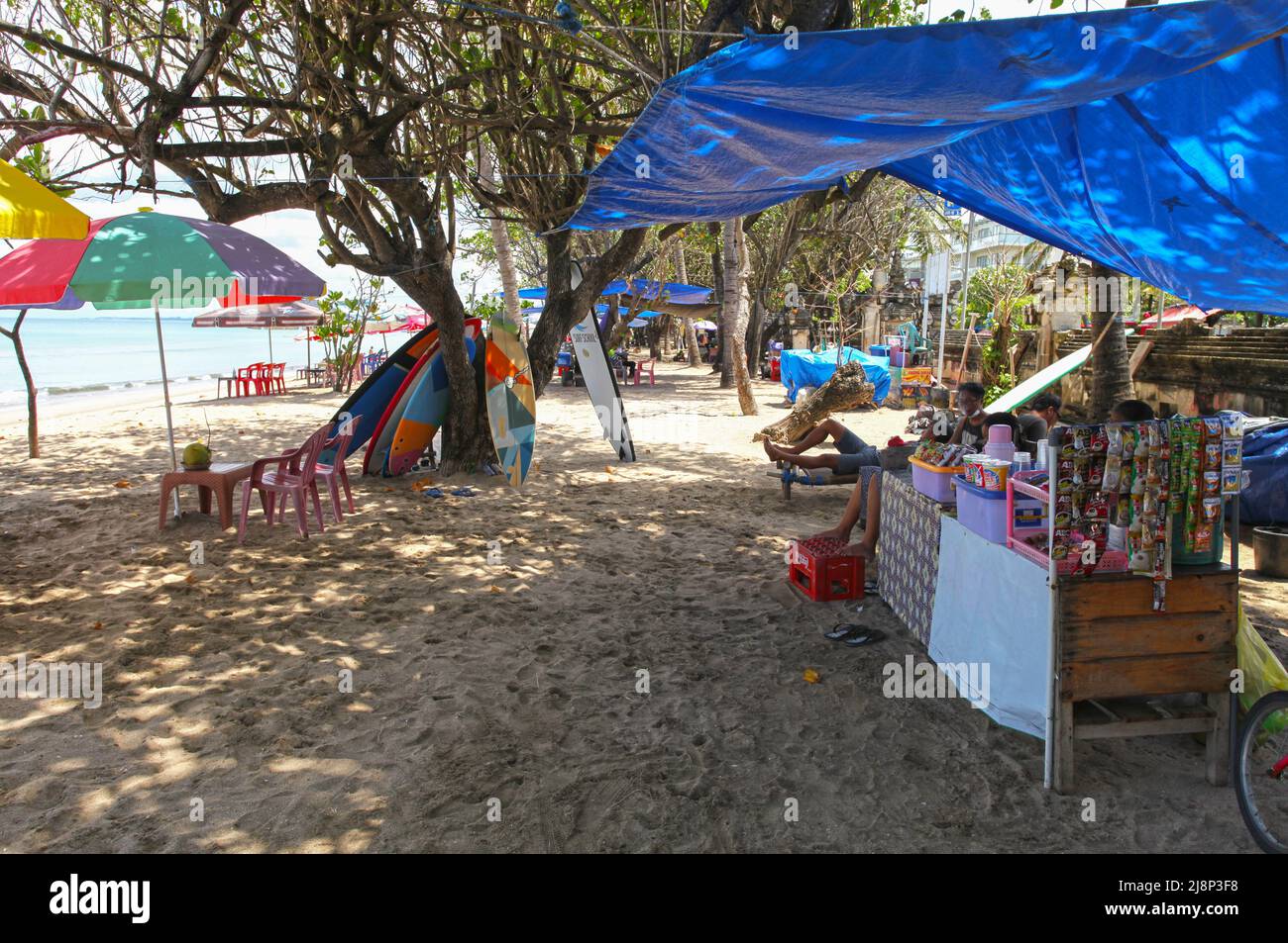 Kuta Beach Szene in Bali, Indonesien im März 2022 während der Pandemie mit wenigen Touristen, Getränkeverkäufern, Sonnenschirmen und einem ruhigen Strand. Stockfoto