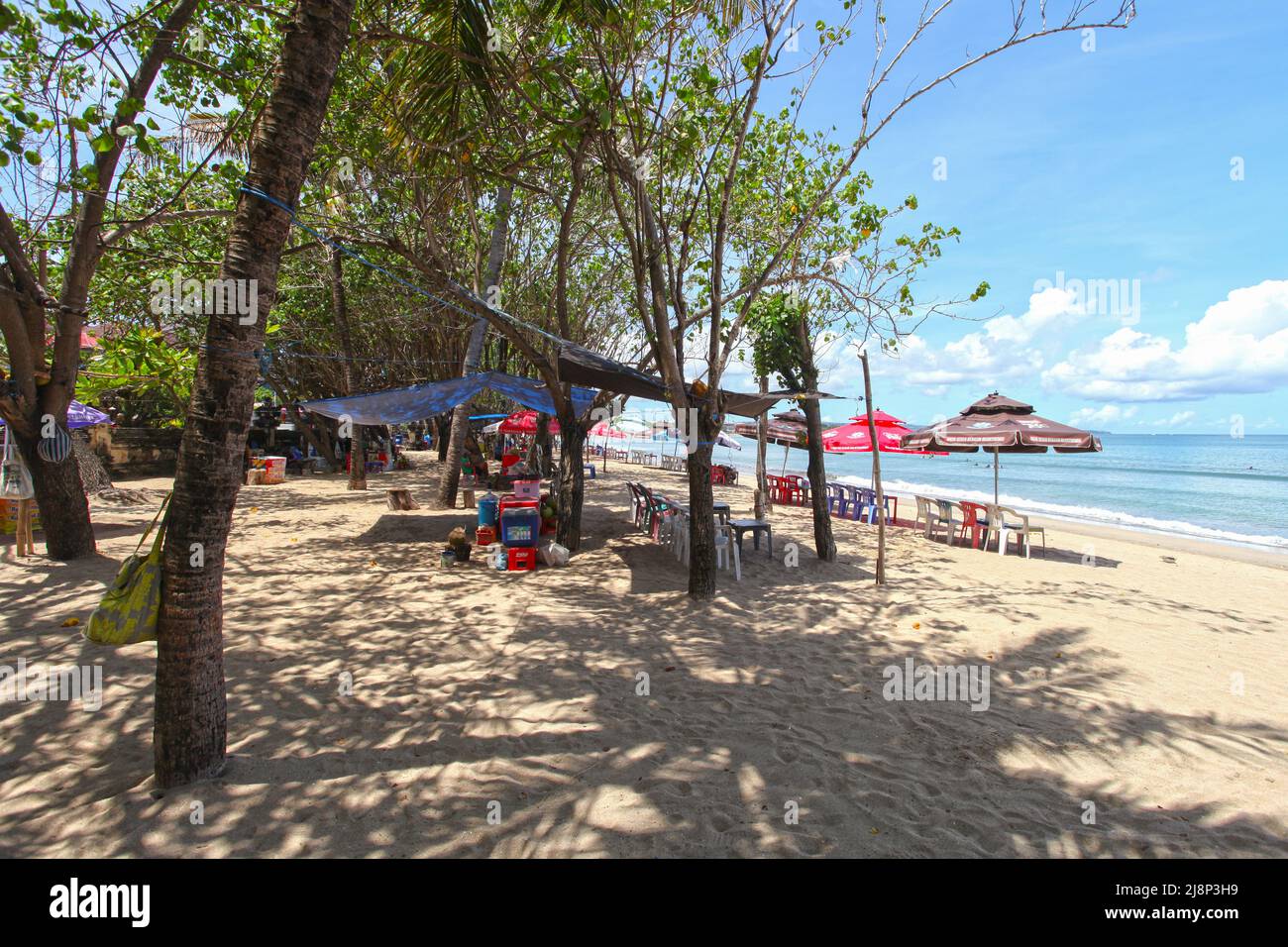 Kuta Beach Szene in Bali, Indonesien im März 2022 während der Pandemie mit wenigen Touristen, Getränkeverkäufern, Sonnenschirmen und einem ruhigen Strand. Stockfoto