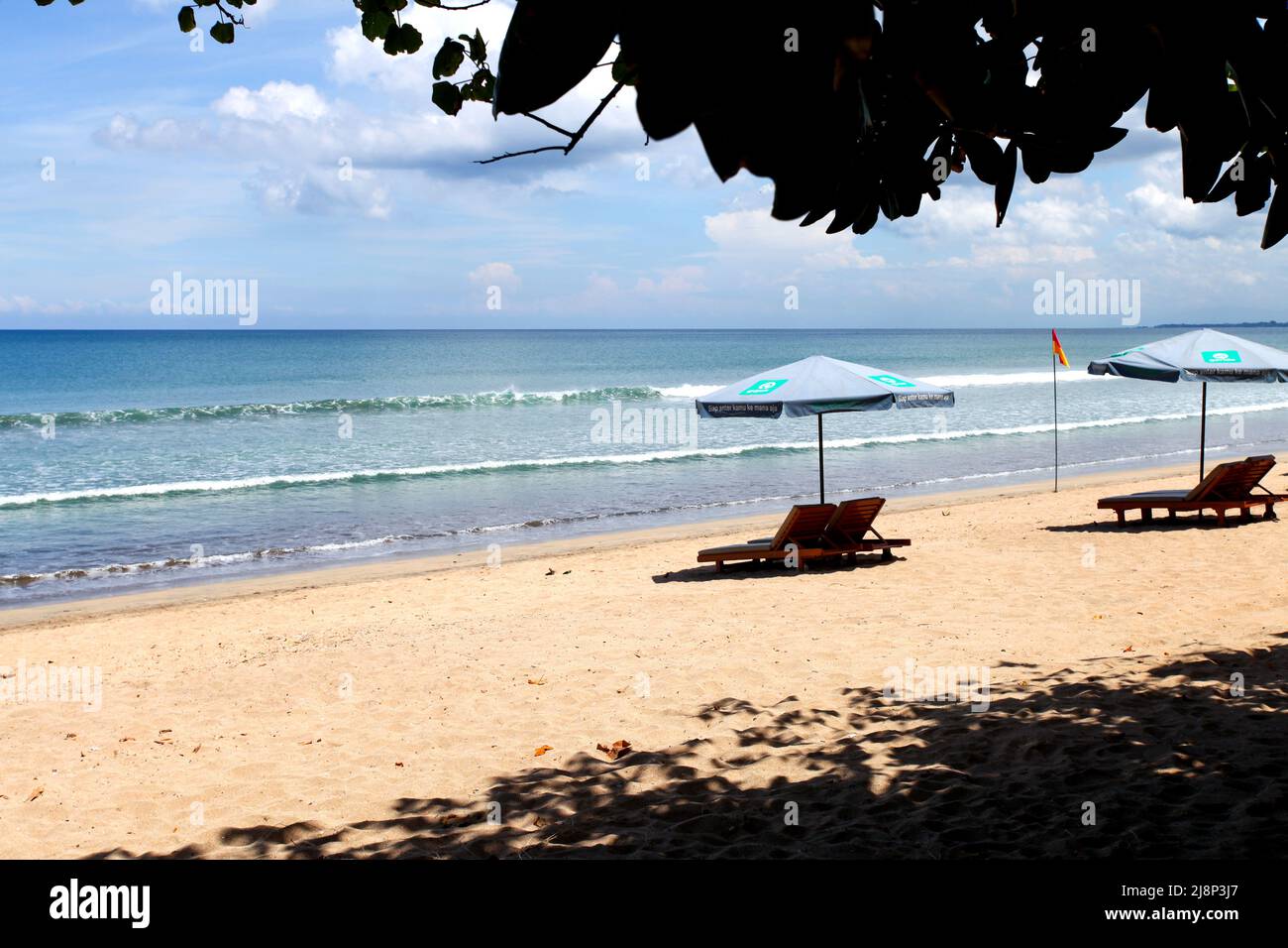 Kuta Beach Szene in Bali, Indonesien im März 2022 während der Pandemie mit wenigen Touristen, Getränkeverkäufern, Sonnenschirmen und einem ruhigen Strand. Stockfoto