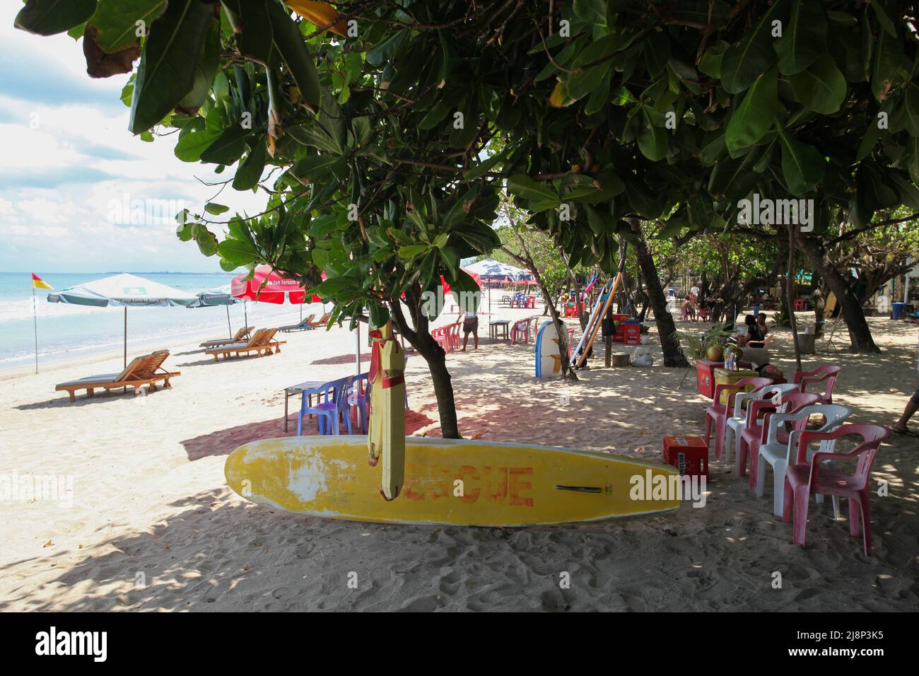 Kuta Beach Szene in Bali, Indonesien im März 2022 während der Pandemie mit wenigen Touristen, Getränkeverkäufern, Sonnenschirmen und einem ruhigen Strand. Stockfoto