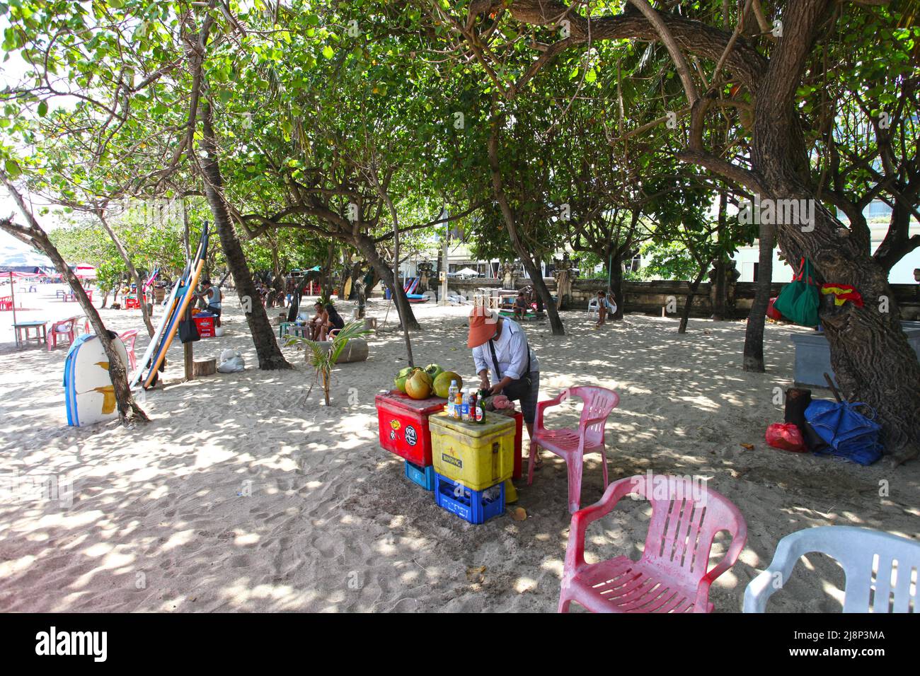 Ein Getränkeverkäufer, der 2022 während der Pandemie im Schatten unter den Bäumen am Kuta Beach sitzt. Es gibt nur wenige Touristen, wenn überhaupt, Stockfoto